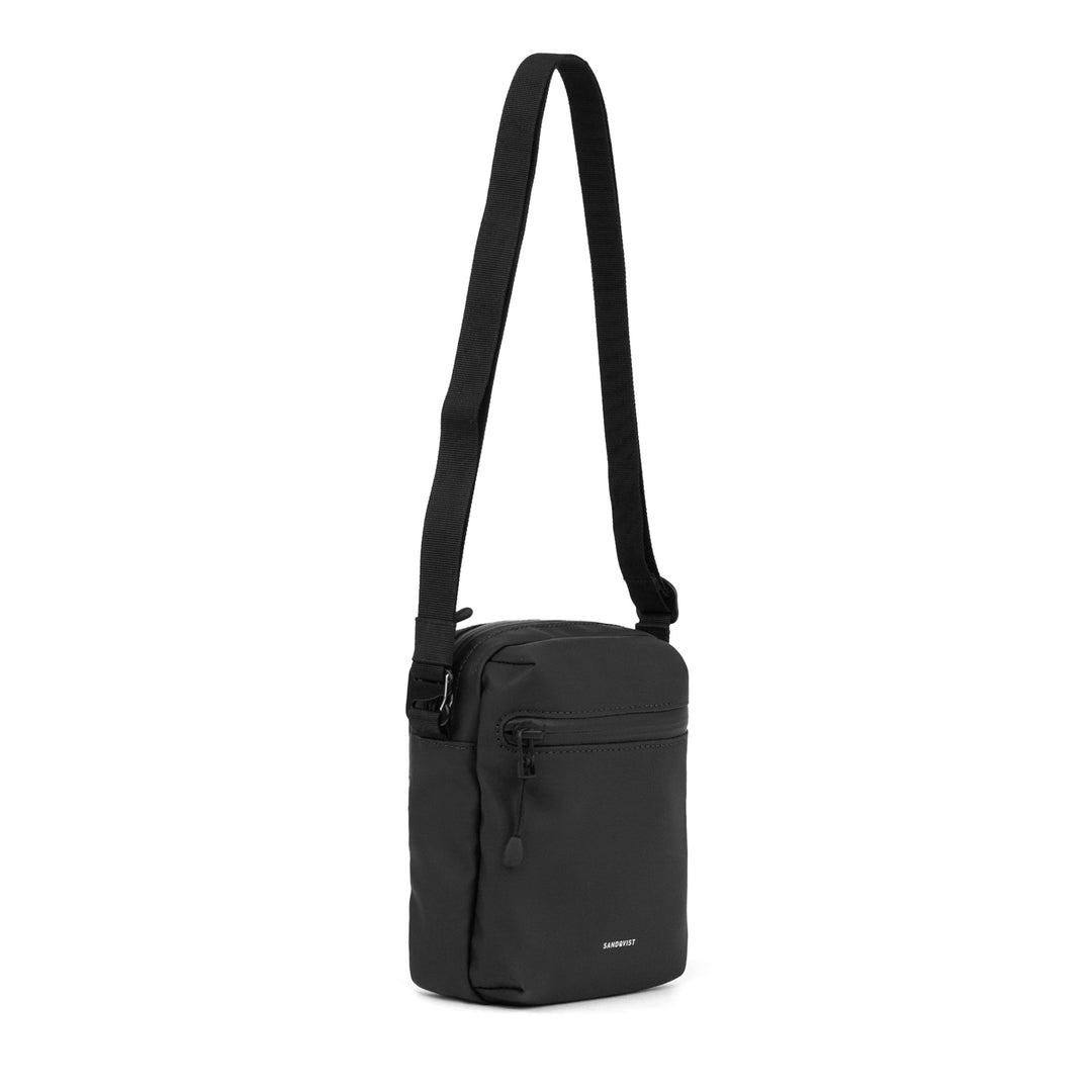 Sandqvist Stream Shoulder Bag in black — three-quarter view with front zip pocket and strap