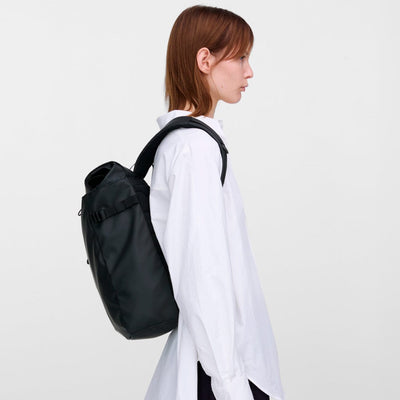 Model wearing the Sandqvist slim rolltop M in black over one shoulder, highlighting its clean look and practical everyday use