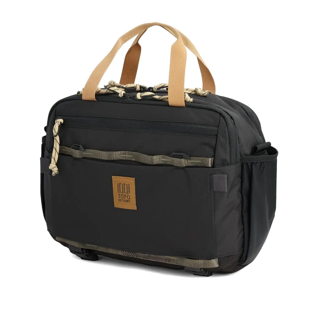 The Mountain Cross Bag 17L in black and neutral — angled side view