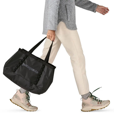 Woman walking with black tote in hand, functional and lightweight style
