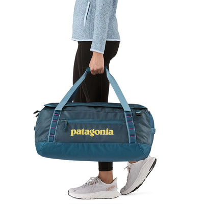 Female traveler carrying tidal teal Patagonia duffel on the back, functional for long hauls