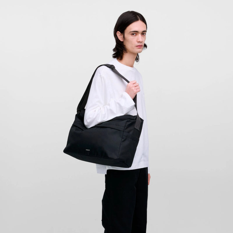Lifestyle photo of a unisex urban messenger bag, styled for daily commuting, cycling, and weekend city life