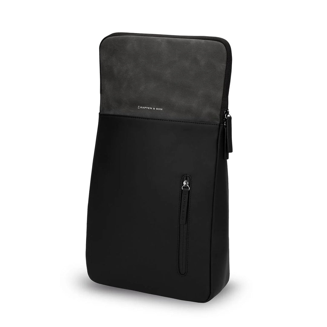 Black Vallen flap lifted to reveal the top-access zip compartment and front vertical pocket