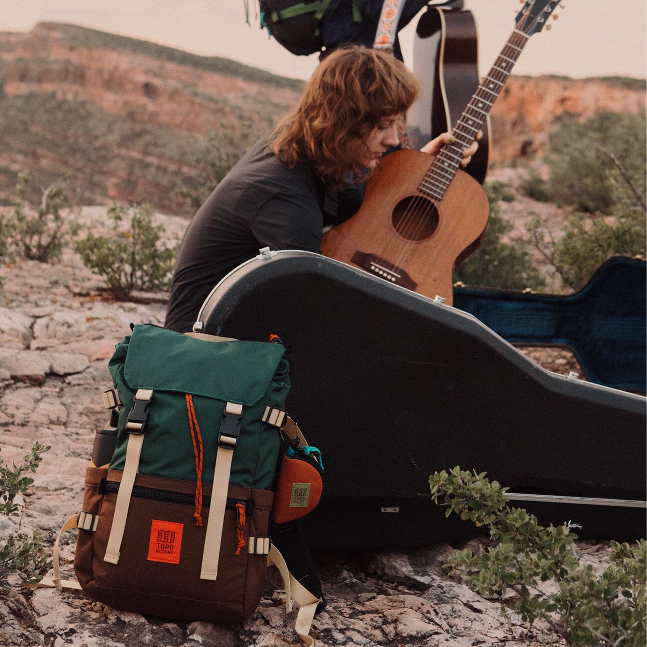 femme camping jouer guitar avec rover classic pack posé devant elle