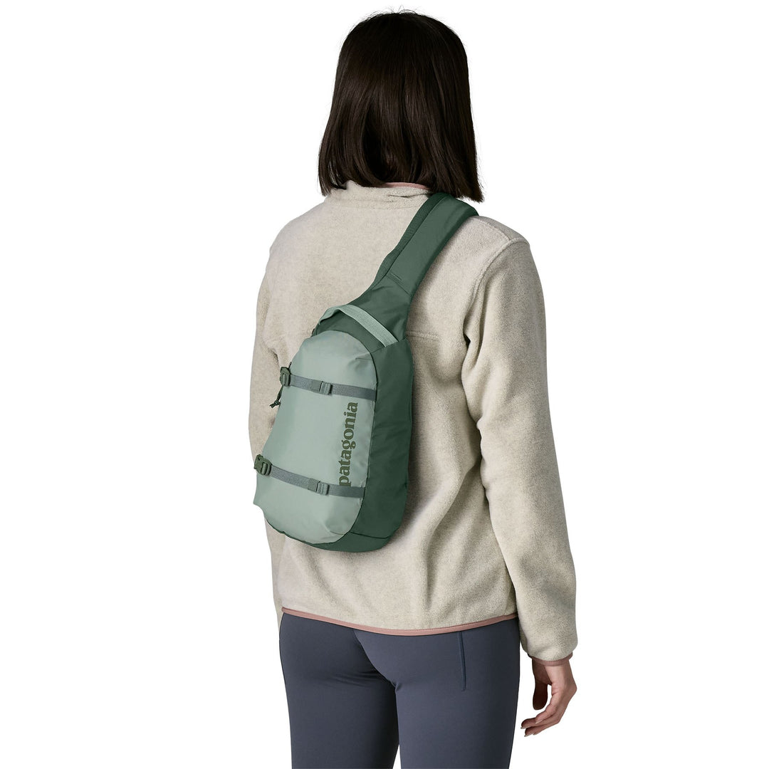 Woman wearing the Atom Sling 8L in Cover Green crossbody, seen from the back