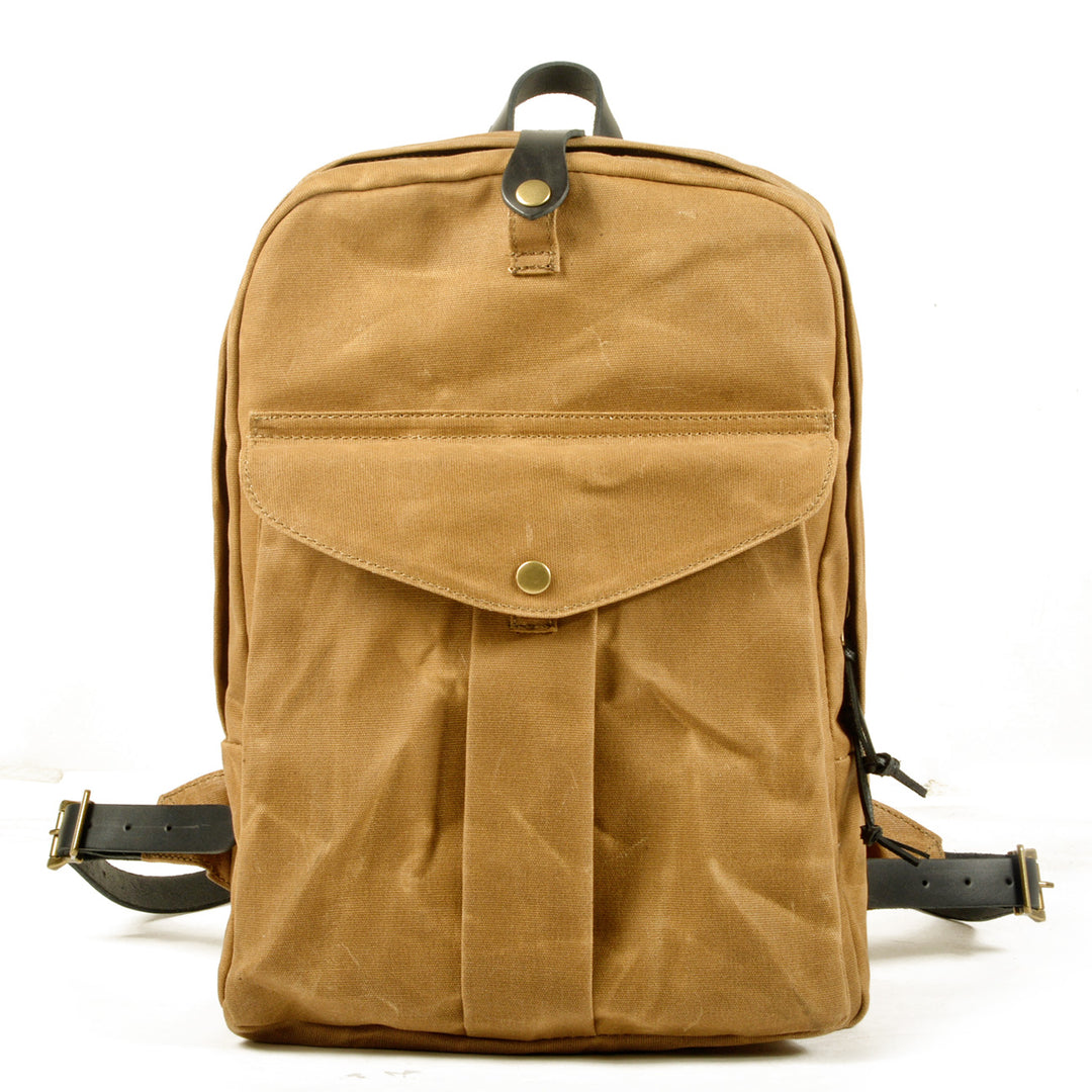 Minimalist canvas backpack in khaki tan with black leather top closure, brass snap, slim vertical silhouette and front utility pocket — Ystad
